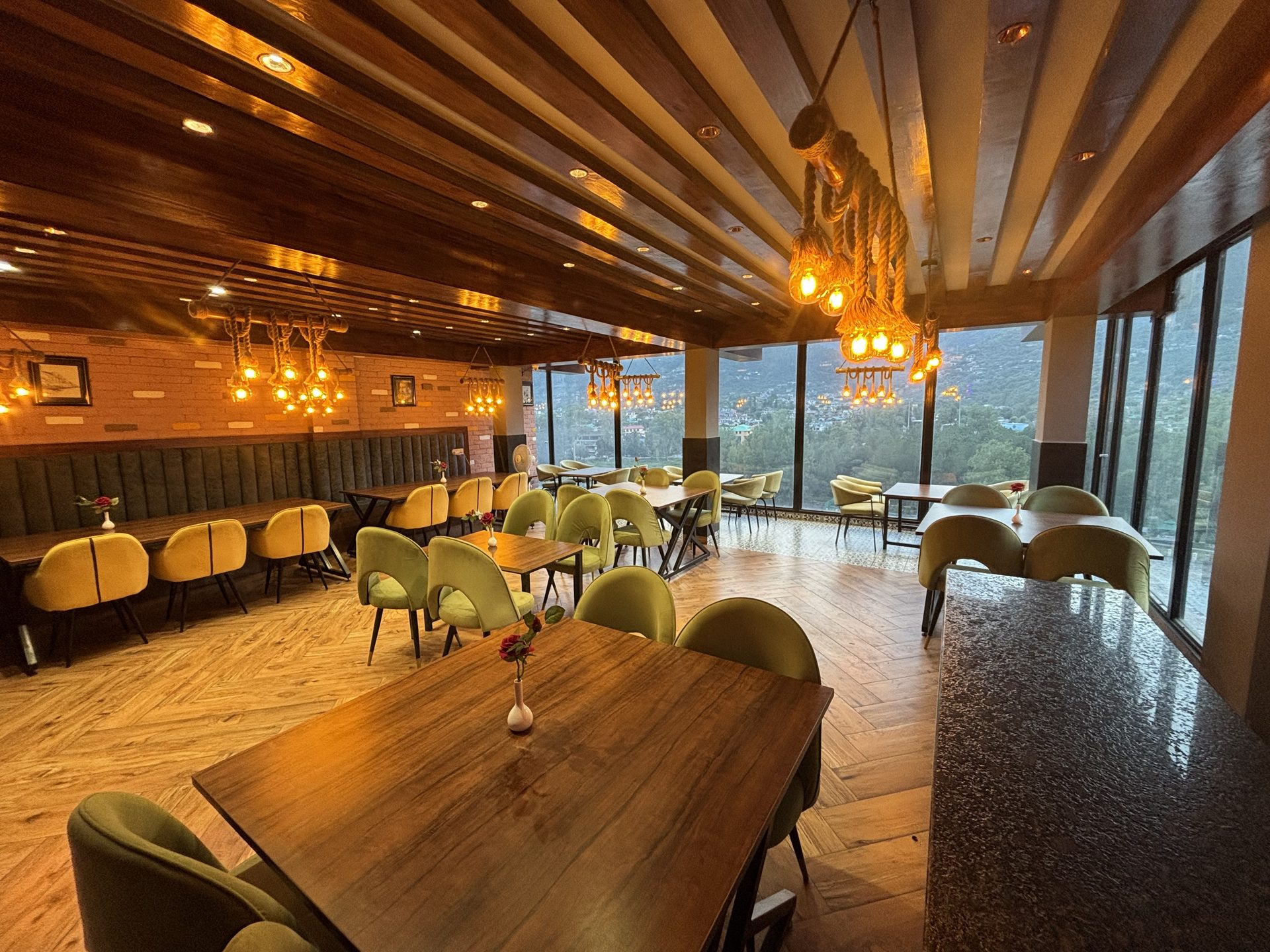 River Heights glass-wall restaurant at dusk overlooking the Kullu valley